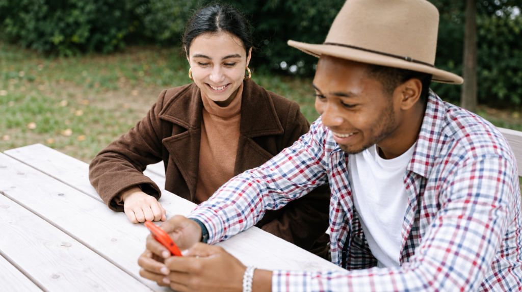 Man and woman sitting together on a park bench looking at a phone